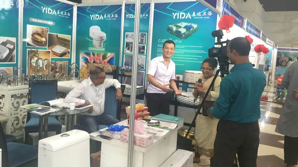 YIDA representative being interviewed at 2017 Bangladesh Expo, with bathroom faucets and ceramic products on display