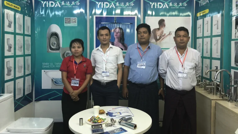 YIDA team with Myanmar clients at 2018 Myanmar Expo, standing in front of toilet and faucet product displays