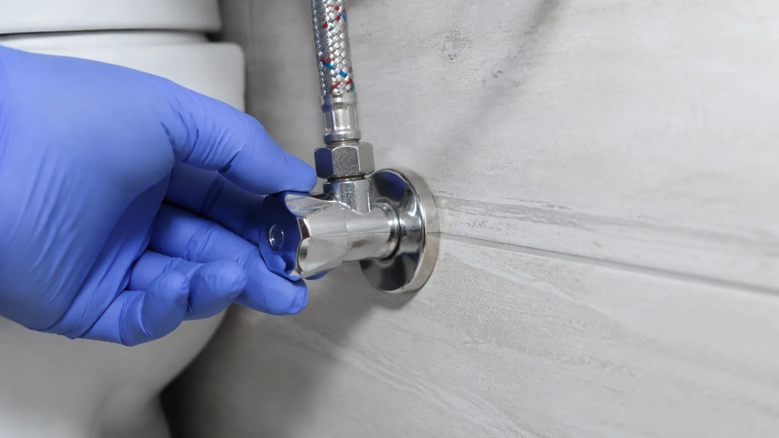 Checking the angle valve and braided hose behind an integrated toilet and basin unit